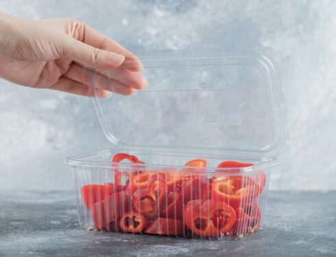 A woman's hand opens a plastic container with red pepper